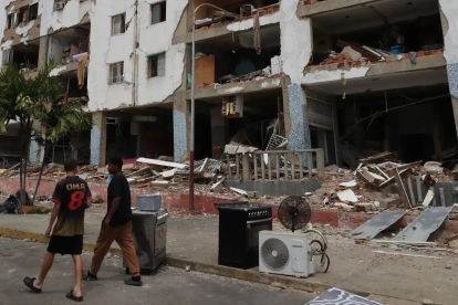 Personas caminan frente a edificios afectados por los terremotos ocurridos en la zona de Caraballeda, en La Guaira (Venezuela).