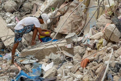 Una persona busca entre los escombros de edificios destruidos por terremotos en Caraballeda.