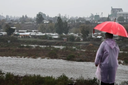Una persona observa el caudal del Río Mapocho al costado de un campamento en riesgo de inundación en la comuna de Talagante (Chile)