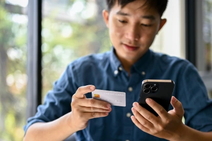 Uso de tarjeta y celular en una transacción digital, reflejo de operaciones que pueden generar errores de transferencia.