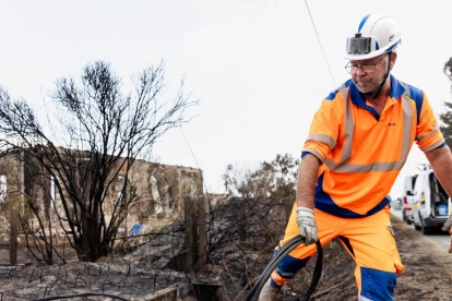Personal de NGE Energie Solutions asegura las líneas eléctricas frente a viviendas dañadas por el fuego tras los incendios forestales en Le Porge, Francia.