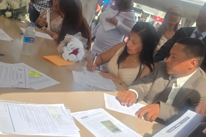 Una de las parejas firma el acta que oficializa su unión durante el matrimonio colectivo celebrado en Parque Samanes.
