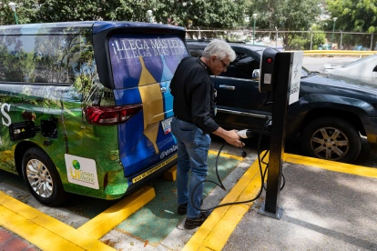 Una persona recarga su carro con electricidad, se multiplican estos puntos de carga en el mundo.