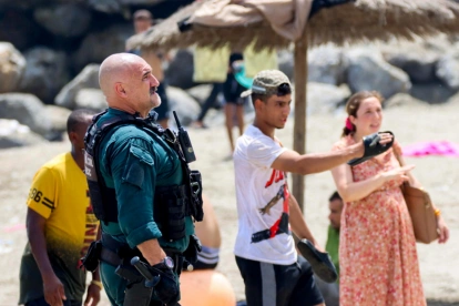 Un agente coordina con vecinos en la playa de Ceuta durante la llegada masiva de migrantes desde Marruecos.