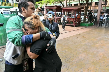 Familiares de una víctima de un tiroteo escolar guardan luto mientras los cuerpos de los fallecidos son introducidos en ambulancias en la escuela del distrito de Bang Kruai, provincia de Nonthaburi, el 7 de agosto de 2026.