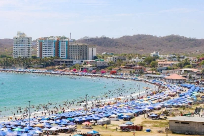 Referencial.Turistas disfrutan de la playa bajo sombrillas en la Costa ecuatoriana, mientras el Inamhi anticipa condiciones variables para el feriado.