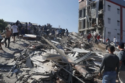 Personas caminan sobre los escombros de un edificio colapsado este lunes, en Cali (Colombia).