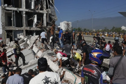 Personas caminan sobre los escombros de un edificio colapsado este lunes, en Cali (Colombia)