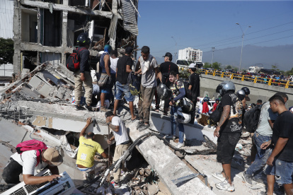 Personas caminan sobre los escombros de un edificio colapsado este lunes, en Cali (Colombia). Al menos 20 edificios sufrieron graves daños por consecuencia del terremoto de magnitud 7,4 que sacudió la mayor parte del país, con epicentro en la zona del Pacífico.