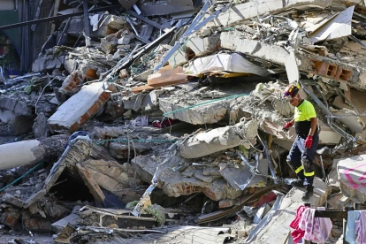 Un integrante de organismos de socorro camina sobre los escombros de una edificación destruida tras el terremoto de magnitud 7,4 que sacudió la víspera la mayor parte de Colombia, este martes en Pereira (Colombia).