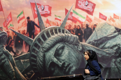Una mujer iraní camina junto a un cartel antiestadounidense en la plaza Enghelab en el centro de Teherán, Irán, el 13 de agosto de 2026.