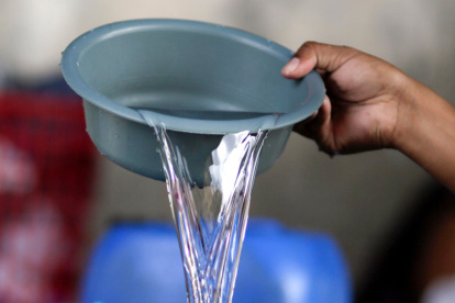El hondureño Darwin Ordoñez llena un recipiente con agua este 14 de agosto de 2026, en Tegucigalpa (Honduras).