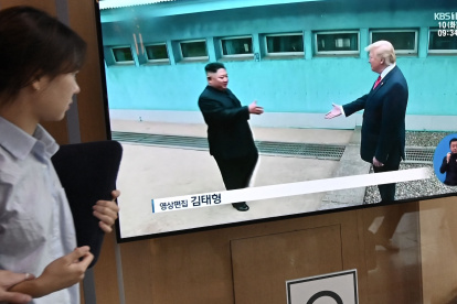 Una mujer pasa junto a una pantalla de televisión que muestra reunión entre el presidente Donald Trump y el líder norcoreano Kim Jong Un, en estación de tren de Seúl.