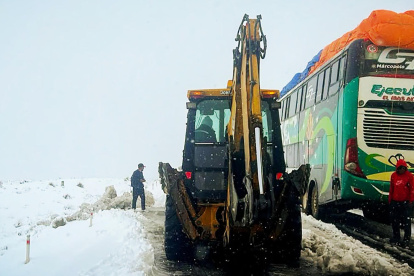 Operarios trabajando con maquinaria amarilla para limpiar una carretera durante una nevada en La Paz (Bolivia).