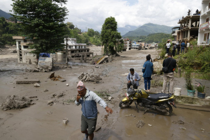 Campesinos avanzan entre el lodo en Trishuli, en el distrito nepalí de Nuwakot, tras una riada repentina.
