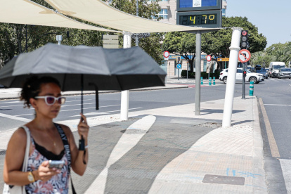 Una mujer se protege con un paraguas del intenso sol el 19 de agosto de 2026 en la plaza América de Valencia.