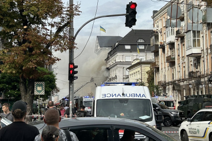 Personas observan cómo rescatistas trabajan para extinguir un incendio tras un ataque aéreo en Kiev.