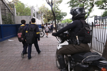 Agente policial custodia el ingreso de estudiantes a un colegio en el norte de Guayaquil.