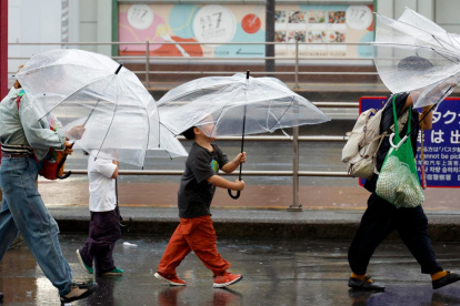 Personas se cubren de las lluvias causadas por el tifón Dujuan en Tokio, Japón.