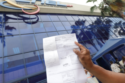 Una persona presenta su planilla de luz en CNEL.