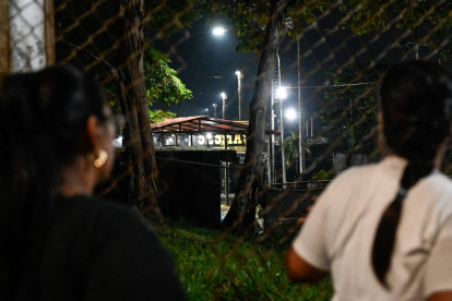 Unas mujeres miran a través de una valla durante una vigilia para exigir la liberación de los presos políticos venezolanos frente a la prisión El Rodeo I en Guatire.