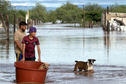 Personas cruzan en medio de una inundación causada por el paso de la tormenta tropical Polo en Guaymas al sur de Sonora (México).