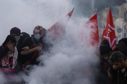 Estudiantes de secundaria permanecen en medio de gases lacrimógenos mientras estallan enfrentamientos entre estudiantes y la policía antidisturbios.