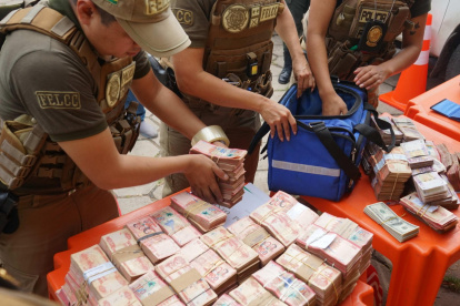 Integrantes de la Fuerza Especial de Lucha Contra el Crimen (FELCC) de Bolivia cuentan billetes que fueron encontrados en una ambulancia.