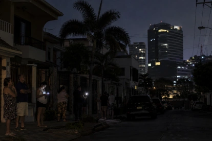 Vecinos permanecen en una calle oscura durante un corte de luz en Guayaquil.