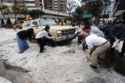 Ciudadanos colaboraron en el retiro del hielo acumulado sobre los vehículos que quedaron cubiertos por la fuerte granizada registrada en Quito.