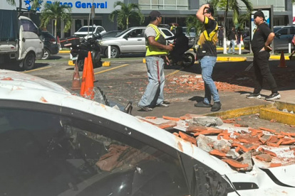 Personas observan un vehículo afectado por los restos de un edificio en Ciudad de Panamá, tras un terremoto de magnitud 7,7 que sacudió el país este viernes 9 de octubre.