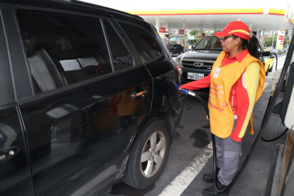 Una trabajadora de una gasolinera despacha el combustible para un carro.