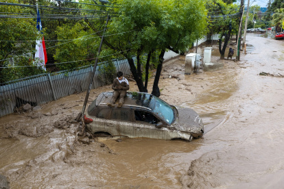 Una persona se refugia sobre un vehículo afectado por un aluvión, el jueves 8 de octubre de 2026, en la comuna de Las Condes, en Santiago de Chile.