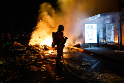 Un bombero francés interviene ante barricadas en llamas en una calle.