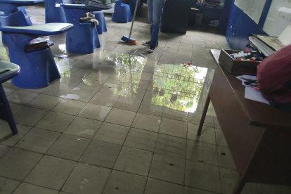 Un trabajador de una escuela en Guayaquil intenta retirar el agua acumulada en un aula.