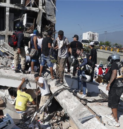 Personas caminan sobre los escombros de un edificio colapsado este lunes, en Cali (Colombia). Al menos 20 edificios sufrieron graves daños por consecuencia del terremoto de magnitud 7,4 que sacudió la mayor parte del país, con epicentro en la zona del Pacífico.
