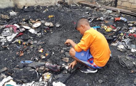 El pequeño Daniel (nombre protegido) busca entre los escombros quemados algún implemento que sirva para levantar el lugar. 