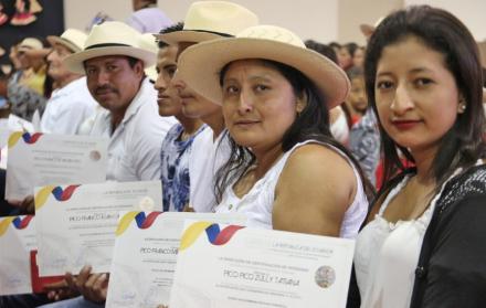 Tres tejedores muestran orgullosos sus acreditaciones.