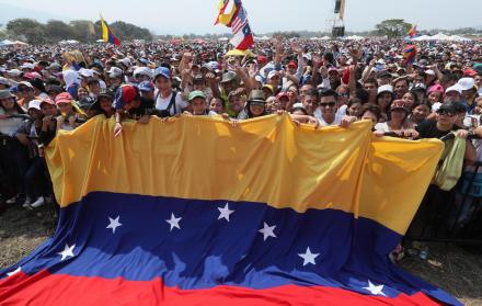 Un grupo de personas sostiene una gran bandera venezolana durante el concierto Venezuela Aid Live este viernes, en el puente fronterizo de Tienditas, en Cúcuta (Colombia).