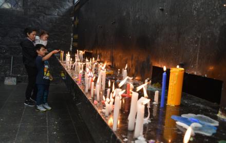 Los feligreses con sus velas primero oran en la gruta de la Virgen del Rosario de Agua Santa.