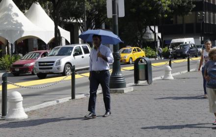 Centro. Un ciudadano se protege del sol mientras camina por la calle Pedro Carbo y su intersección con 9 de Octubre.