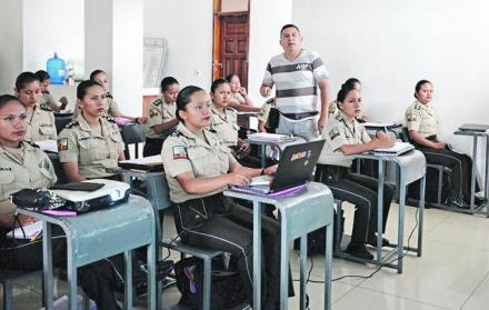 En el salón. Las aspirantes atienden al profesor, quien enseña una de las materias con ayuda de un proyector.