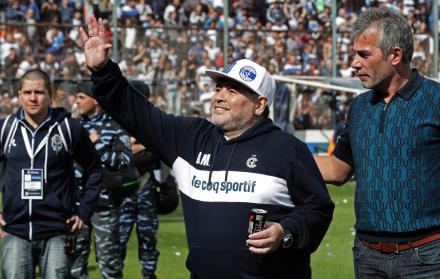 La estrella del fútbol argentino Diego Maradona saluda al público junto al presidente Gabriel Pellegrino.