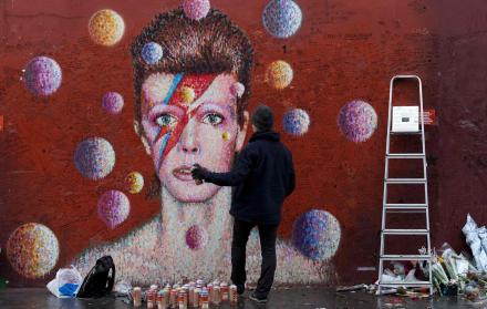 El artista de la calle australiana James Cochran, también conocido como Jimmy C, junto a su mural de David Bowie en Brixton, al sur de Londres, el 7 de enero de 2017, antes del primer aniversario de la muerte del icónico músico.