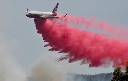 Un avión del Servicio de Bomberos arroja retardante de fuego (polvo rojo) en un incendio forestal fuera de control cerca de Taree, 350 km al norte de Sydney. (AFP)