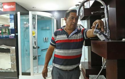 Mercado. Una persona mira la llave para el agua que es de palanca, hay de varios modelos y tamaños.