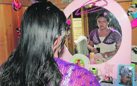Niña alistándose para una fiesta frente a su tocador rosa, el color que prima en su pequeña habitación.