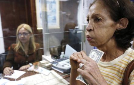 Transacciones. Una mujer venezolana sostiene en las manos algunos dólares, en una oficina de Caracas.