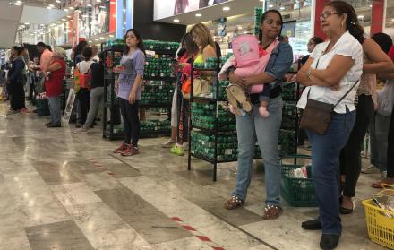 Un grupo de personas espera para pagar sus compras en un local de Caracas.