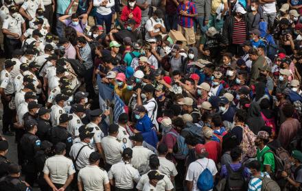 Migrantes hondureños se arrodillan para orar frente a los policías guatemaltecos, el 17 de enero de 2021 desde la aldea Vado Hondo, Chiquimula (Guatemala).